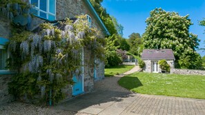 A stone building with a blue door, a small garden, and a pathway leading to a house. - Dulas Bach - sleeps 12 guests  in 6 bedrooms (Colwyn Bay)
