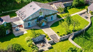 A stone house with a sloped roof, a patio with outdoor seating, and a stone wall surrounding the property. - Dulas Bach - sleeps 12 guests  in 6 bedrooms (Colwyn Bay)