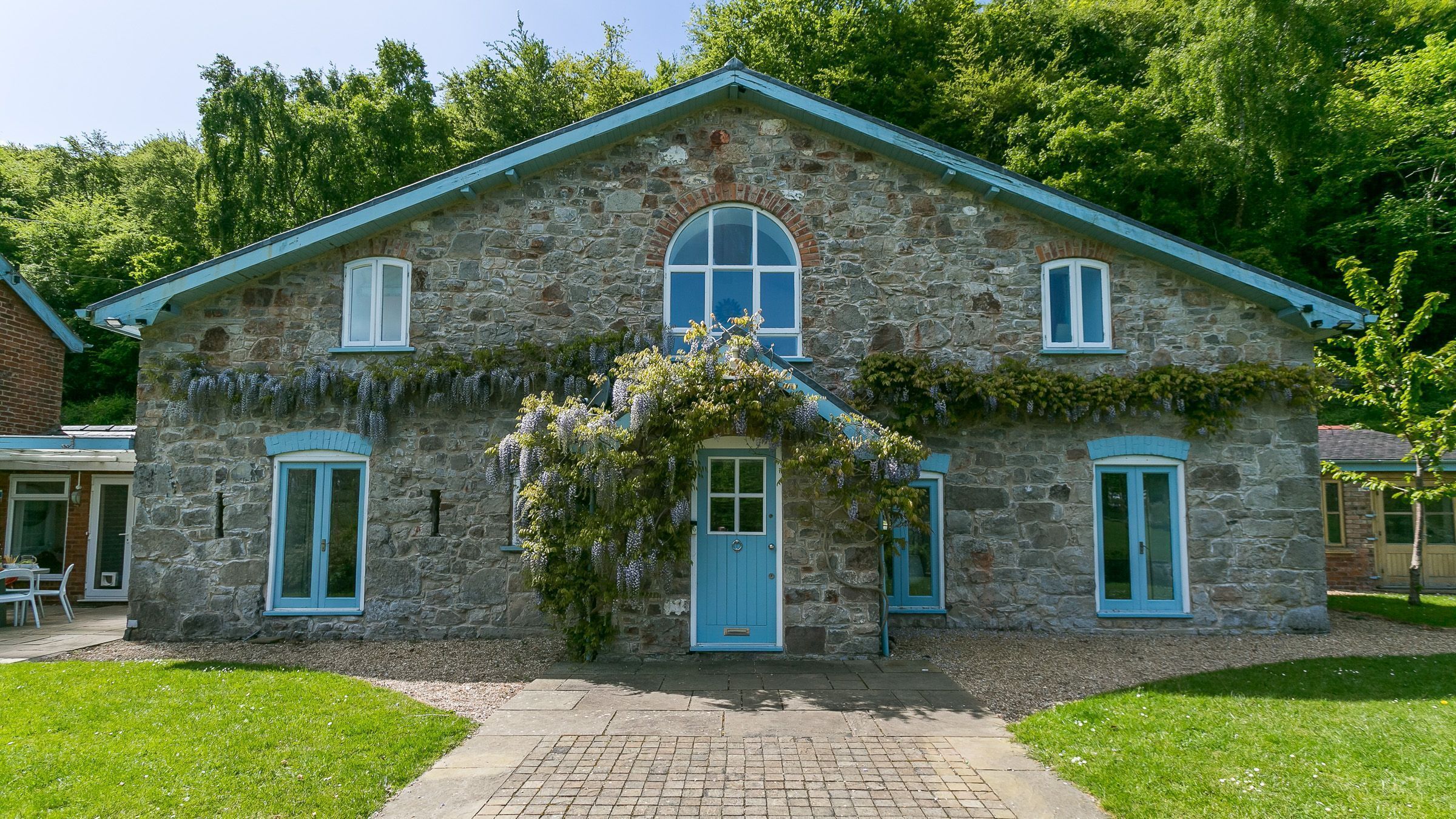A stone house with a blue door, two windows, and a small porch.