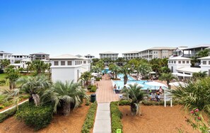 Ein Resort mit mehreren Gebäuden, einem zentralen Poolbereich und Palmen.