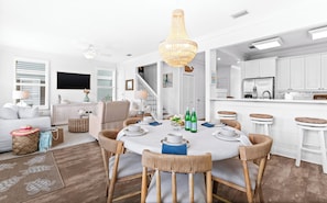 A dining area with a round table, wicker chairs, and a hanging light fixture. - Rare Poolside Seacrest Home Between Alys and Rosemary w/Private Beach Access (Inlet Beach)