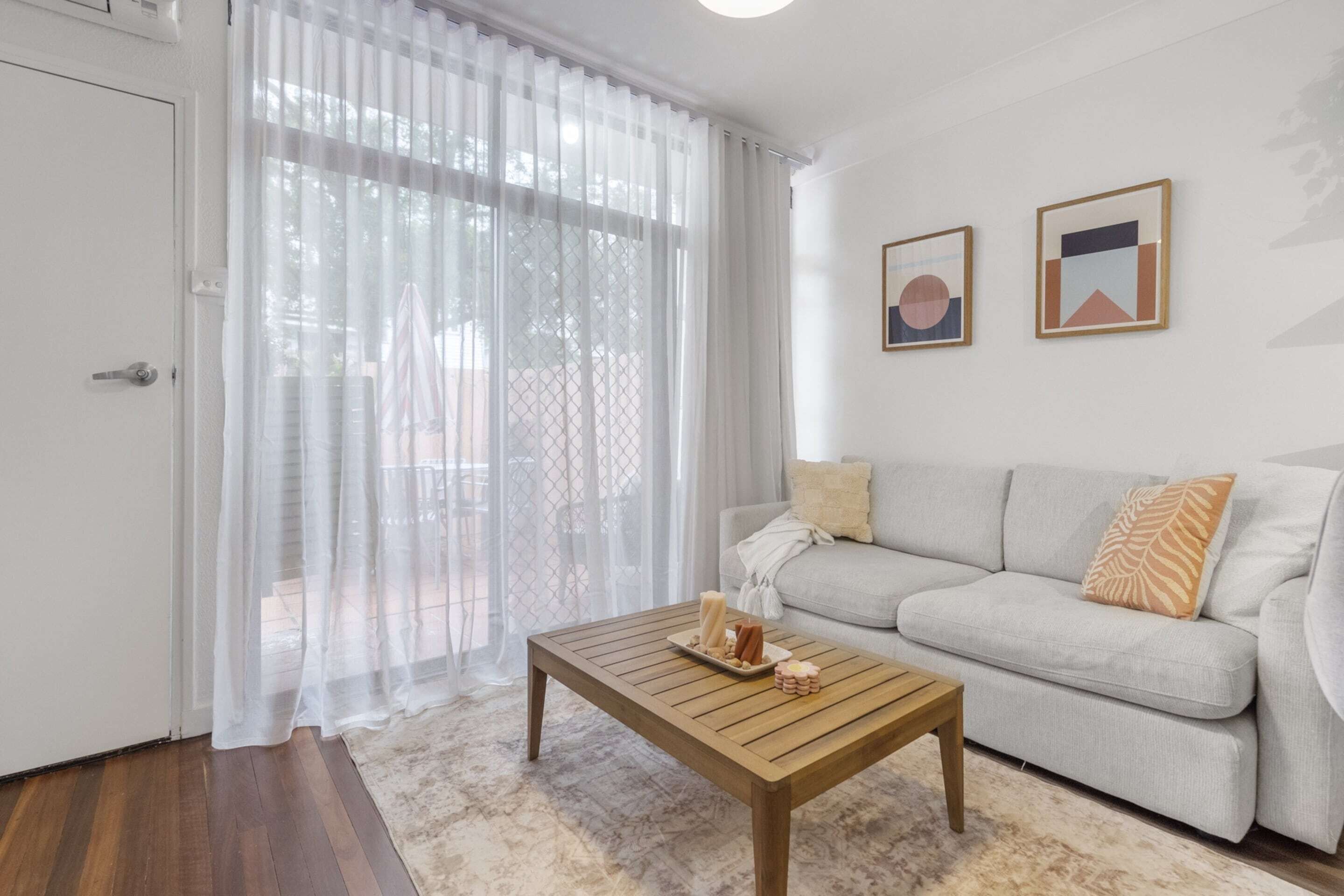 A living room with a sofa, a coffee table with snacks, a door, and two framed pictures on the wall.