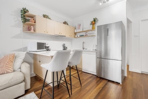 Eine moderne Küche mit Holzschränken, einem Edelstahlkühlschrank und einer weißen Arbeitsplatte.