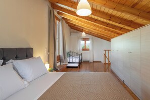 Ein Schlafzimmer mit einem Bett, Holzboden, einem weißen Kleiderschrank und einem Fenster.