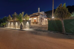 Ein Haus mit einer Steinmauer, einem gepflasterten Weg und einem grünen Zaun.