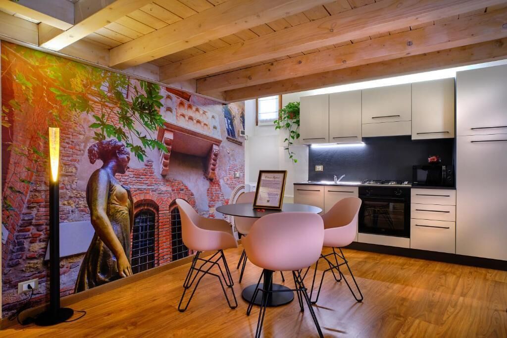 Una cocina moderna con armarios blancos, una estufa negra y un comedor con una mesa redonda y sillas rosadas.