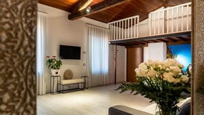 A modern living room with a wooden ceiling, a flat-screen TV, a bench, and a potted plant. - Palazzo Ristori (Verona)