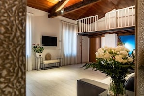 Una sala de estar moderna con techo de madera, un televisor de pantalla plana, un banco y una planta en maceta.