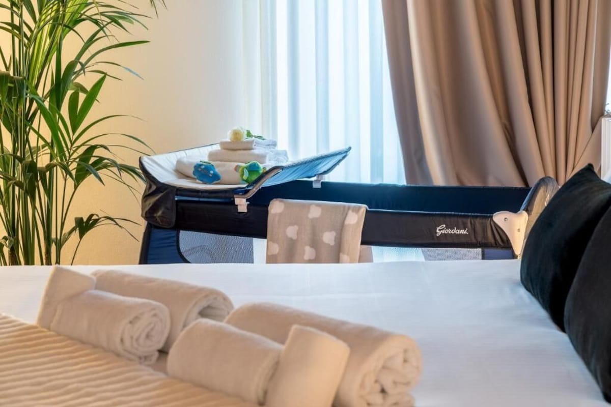 Una habitación de hotel con una cama, una silla, una mesa con toallas y una planta en maceta.