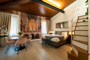 Habitación de hotel con cama, escritorio, silla, mesa de comedor y una escalera.
