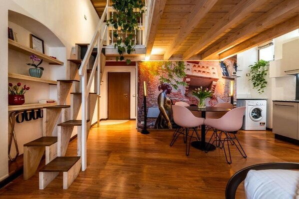 Un interior moderno con una escalera, zona de comedor y cocina.
