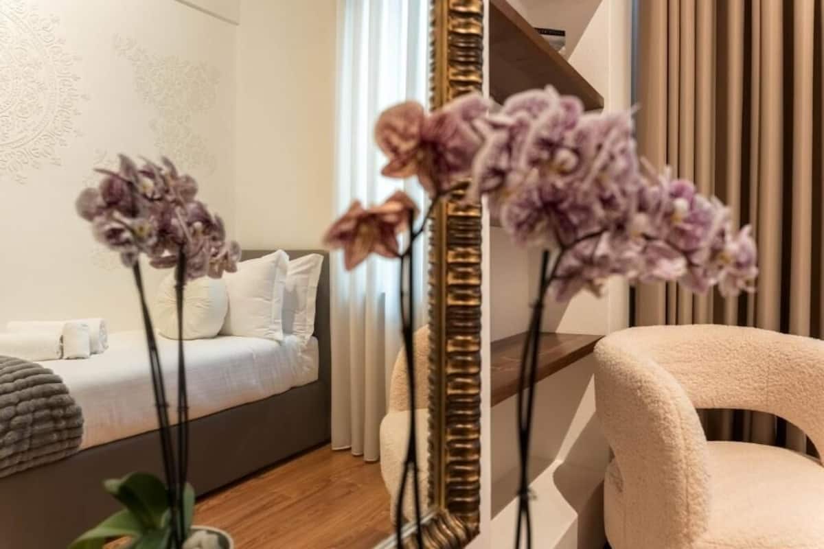 A modern bedroom with a bed, a sofa, a chair, and a mirror.