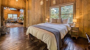 Ein Holzblockhaus-Interieur mit einem großen Bett, einem Essbereich und Blick ins Freie.