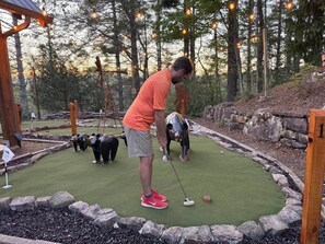 A miniature golf course with a wooden structure, a putting green, and a number one hole. - Luxury Lodge: Mini Golf, Hot Tub, Views, Game Room, Pet Friendly (Gilmer County)