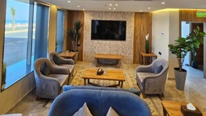 A modern lobby with seating, a flat-screen TV, and large windows.