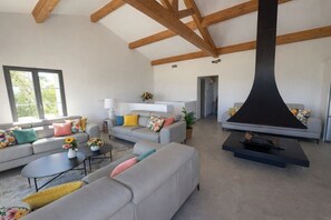Ein geräumiges Wohnzimmer mit hoher Decke, eingebautem Kamin und großen Fenstern.