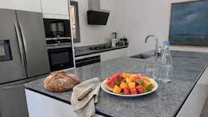 Een moderne keuken met een granieten aanrecht, een brood, een schaal fruit en een waterfles.