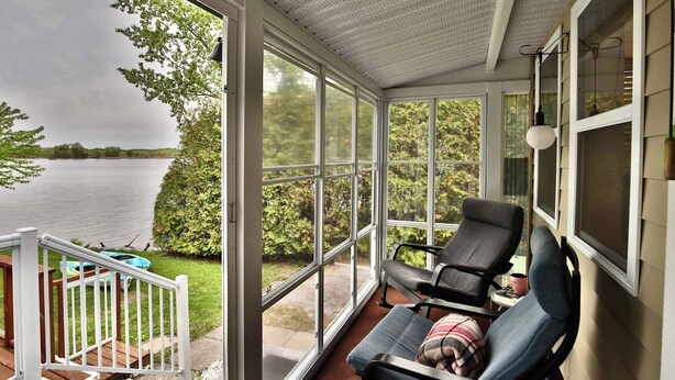A covered porch with a view of a lake, two chairs, and a small table. - River & Nature - Nook Richelieu (Henryville)