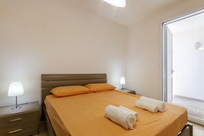 A hotel room with a bed, two bedside lamps, a nightstand, and a view of the outside. - GuestHost - Sabrina House (Torre dell'Orso)