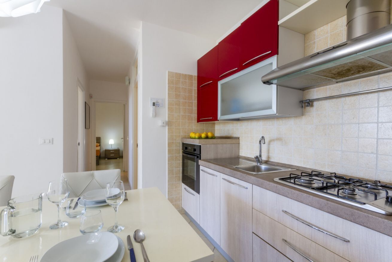 Une cuisine moderne équipée d’une cuisinière à gaz, d’appareils électroménagers en acier inoxydable et de meubles de rangement rouges.