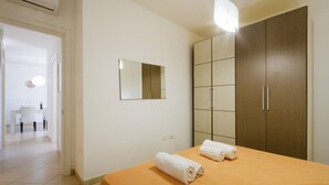 A hotel room with a bed, a wardrobe, a mirror, and a bathroom visible in the background. - Spacious and comfortable 90 sqm villa, ideal for up to 4 guests, equipped with all the comforts for a relaxing holiday in the heart of Salento, including private parking, a large garden, a covered patio, and a furnished terrace, perfect for enjoying rela (Torre dell'Orso)