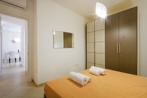 Ein Hotelzimmer mit einem Bett, einem Kleiderschrank, einem Spiegel und einem Badezimmer im Hintergrund.