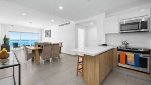 Una cucina moderna con un'isola centrale, una zona pranzo con vista e un'ampia finestra sul mare.