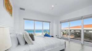 Una camera da letto con un letto, ampie finestre e vista sulla spiaggia.