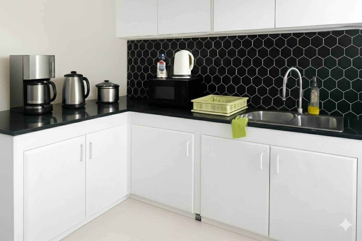 Een moderne keuken met witte kasten, een zwart aanrecht, een koffiezetapparaat, een waterkoker, een magnetron, een afwasschuur en een spoelbak.