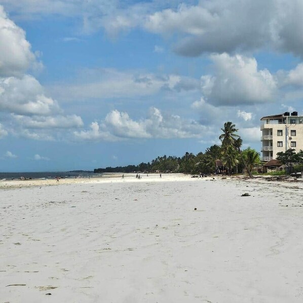 Une plage avec un bâtiment en arrière-plan.