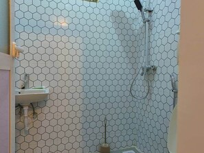 Un baño con un patrón de azulejos hexagonales, un lavamanos y una ducha.