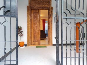 A doorway with intricate woodwork, a potted plant, and a red curtain in the background.