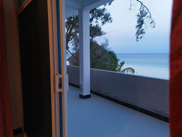 Ein Balkon mit Meerblick, einem weißen Geländer und einer Tür zu einem anderen Raum.