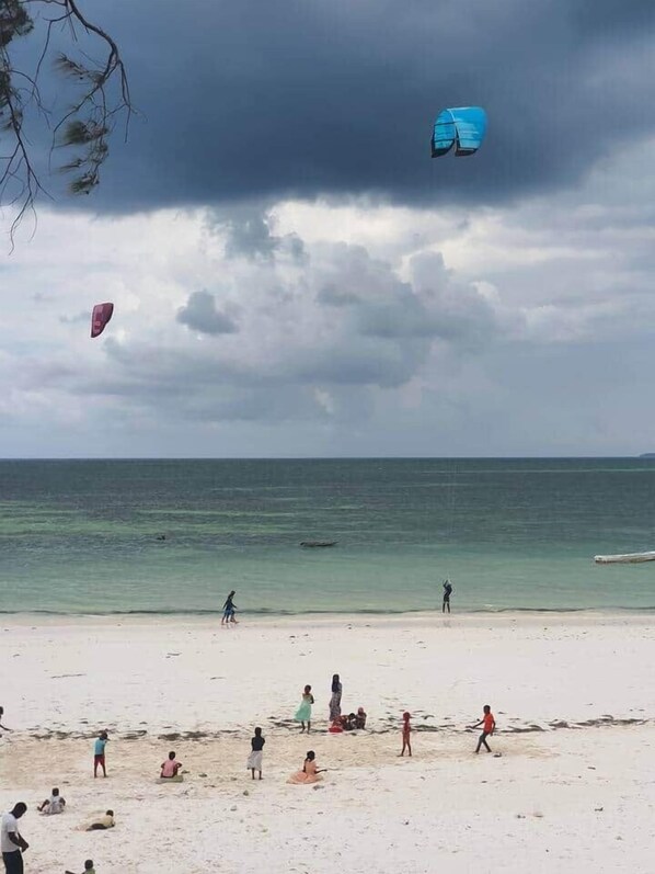 Une plage animée, un ciel dégagé et une mer calme.