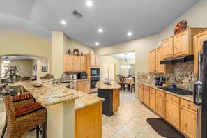 Una cocina amplia con armarios de madera, encimeras de granito y una isla central.