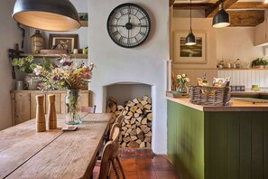 Eine rustikale Küche mit Holztisch, einer Uhr und einem Kamin.