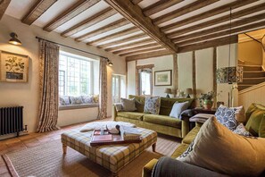 Ein gemütliches Wohnzimmer mit einer Couch, einem Karottenfußhocker und einer Treppe.