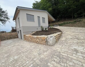 Une maison moderne avec des fondations en pierre, un petit jardin et une allée pavée.