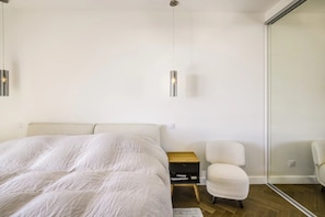 A bedroom with a bed, a nightstand, a chair, and a wall-mounted light fixture. - Perfect 2-Bedroom Apartment with AC, Sea View & Terrace in Charming Nice, Garage (Nice)