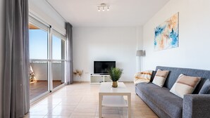A modern living room with a sofa, a coffee table, a TV, and a painting on the wall. - AlmeriaSuite Palm Beach Golf & Pool 1301 (El Ejido)
