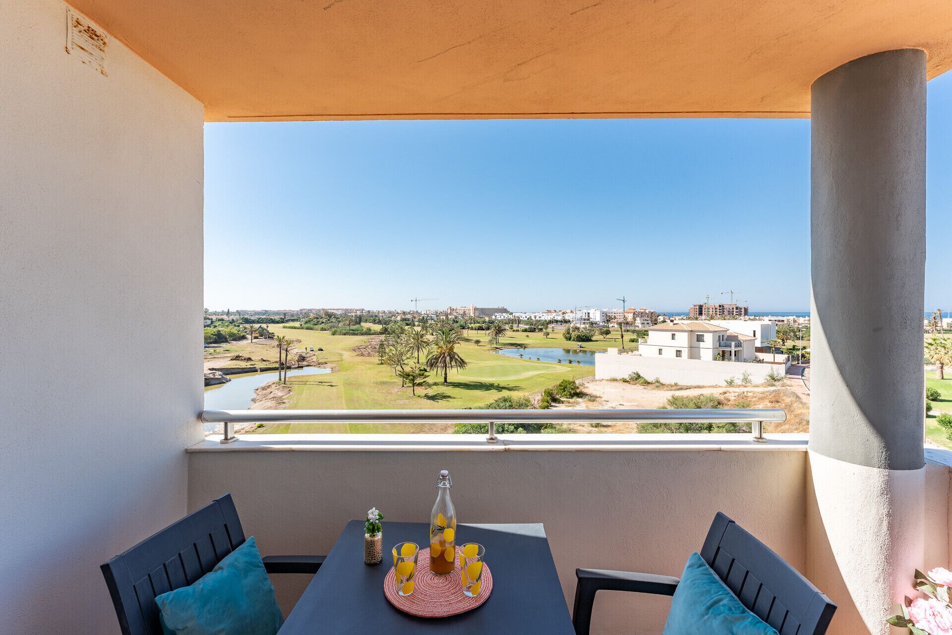 A balcony with a table, chairs, and a bottle of orange juice.
