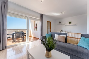 Ein modernes Wohnzimmer mit einer Couch, einem Couchtisch und einem Balkon mit Tisch und Stühlen.