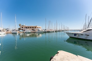 Ein Yachthafen mit mehreren Segelbooten, ein Gebäude mit Balkon und ruhiges Wasser, das die Boote reflektiert.
