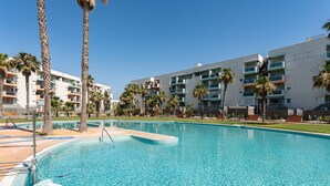 A swimming pool with clear blue water, surrounded by palm trees and modern apartment buildings. - AlmeriaSuite Palm Beach Golf & Pool 7301 (El Ejido)
