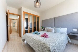 Une chambre à coucher comprenant un lit, une table de chevet, une commode, un miroir et une armoire.