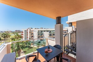 Un balcon avec une table, des chaises, une bouteille de champagne et un arrangement floral.