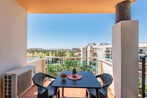 Un balcon avec une table, des chaises et une bouteille de champagne.