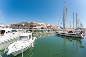 A marina with boats docked, a building with multiple balconies, and clear skies. - AlmeriaSuite Palm Beach Golf & Pool 6303 (El Ejido)