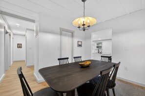 A dining area with a dark wooden table, black chairs, and a chandelier.