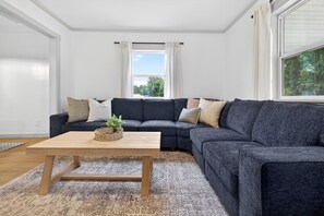 A living room with a dark grey sectional sofa, a wooden coffee table, and a patterned rug. - Cozy Crane Cottage, WestGate~3 Bedroom 2 Bathroom~ (Crane)